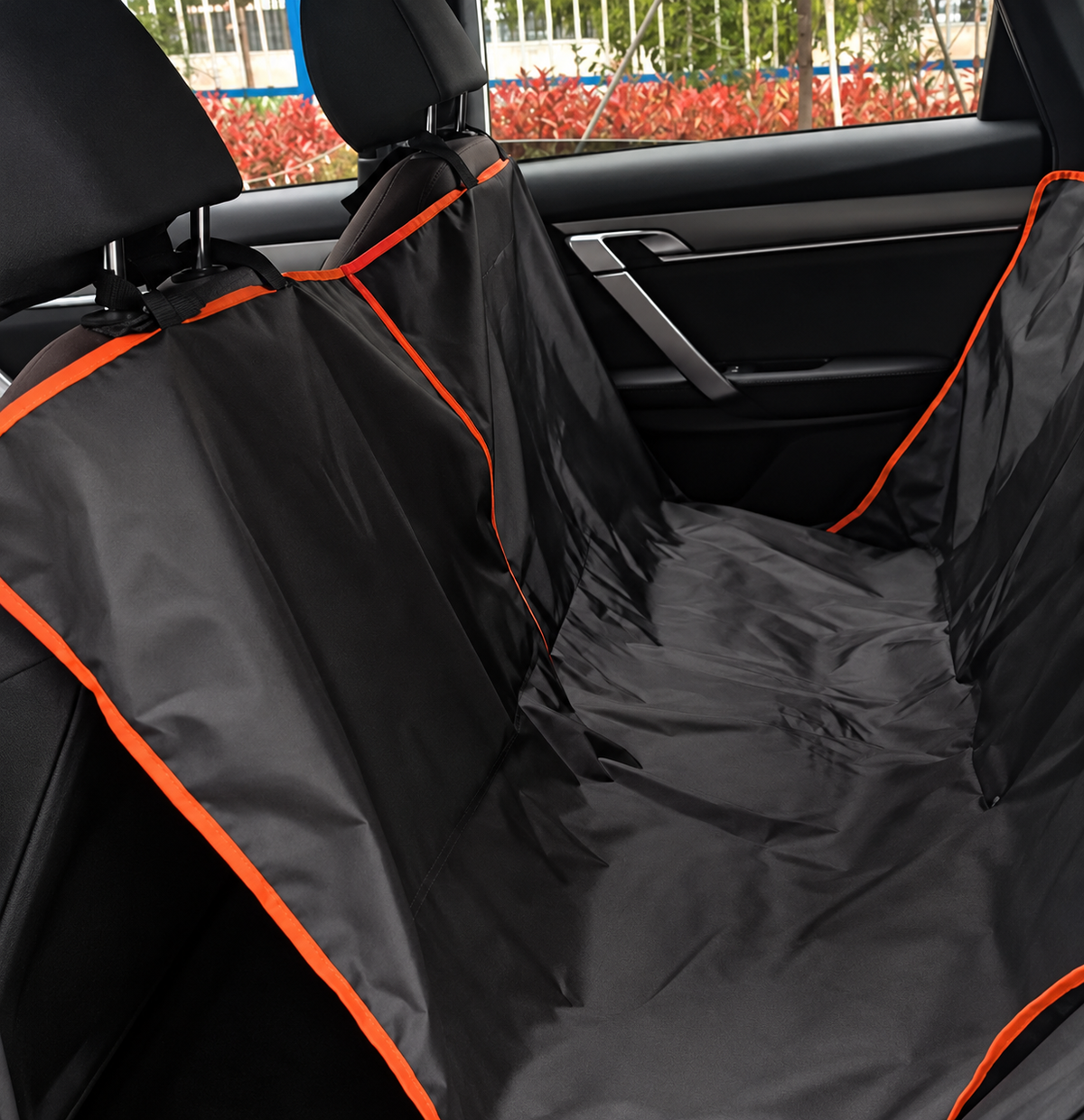 Black hammock-style rear-seat dog cover with orange piping installed around the car headrests